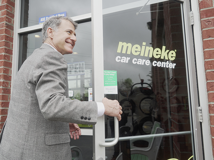 Smiling man entering Meineke car care center